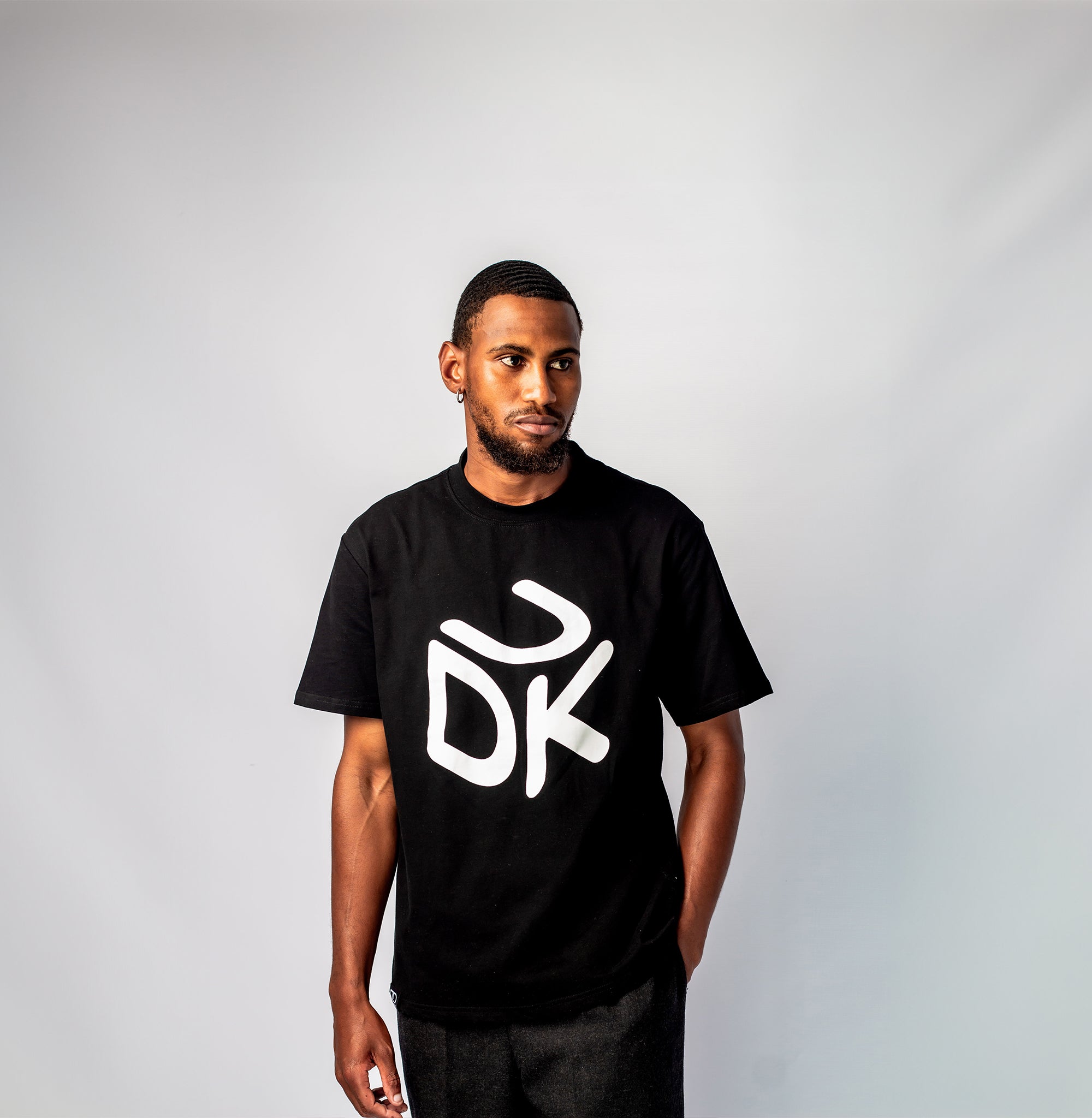 Black T-shirt with short sleeves and round neckline, featuring a white stylized "UDK" box logo on the front.