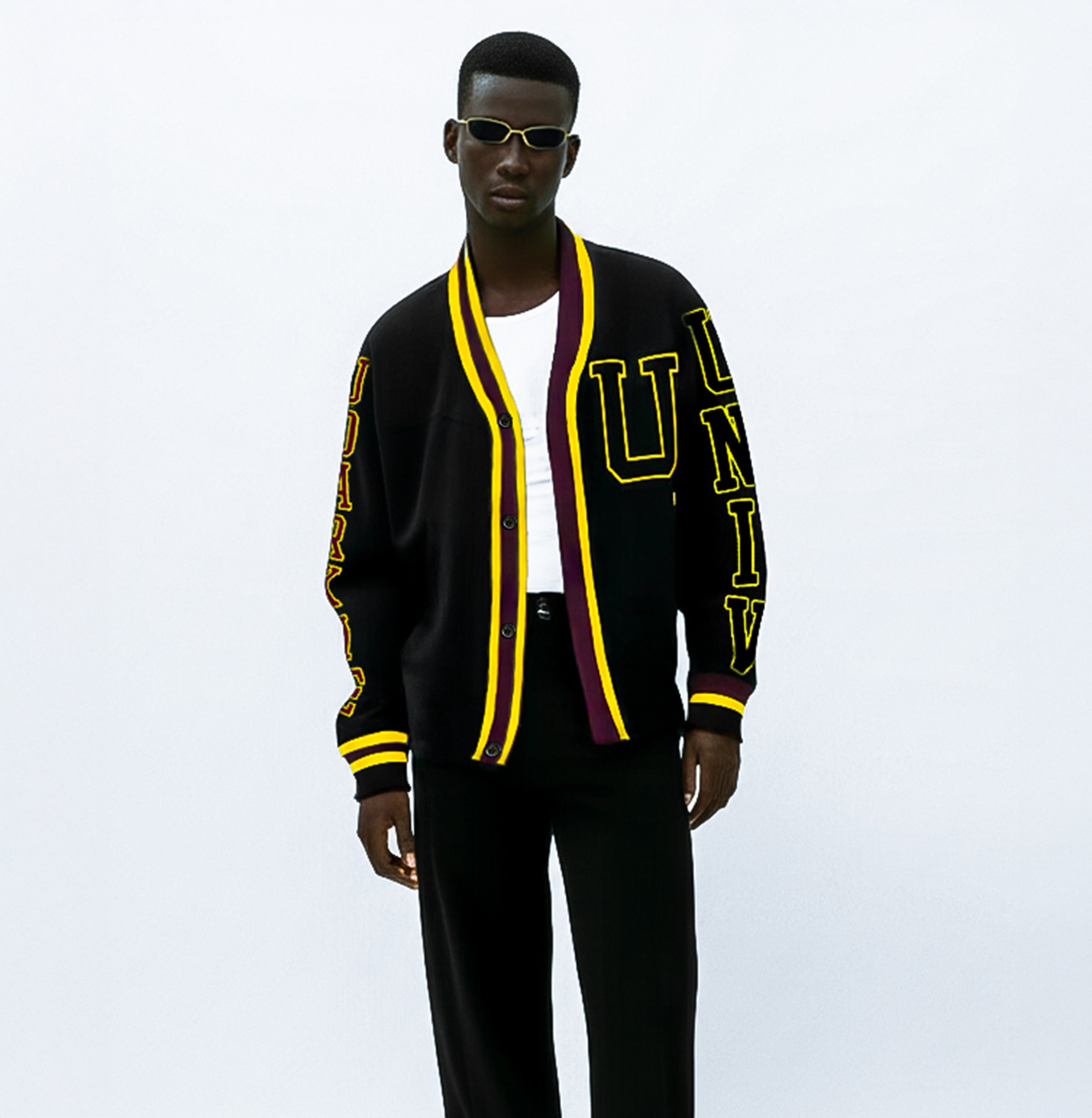 Black varsity cardigan with yellow and maroon trim, with a large yellow "U" on the chest and "UNIV" text on the left sleeve and "UDARKIE" on the right sleeve, worn over a white shirt.