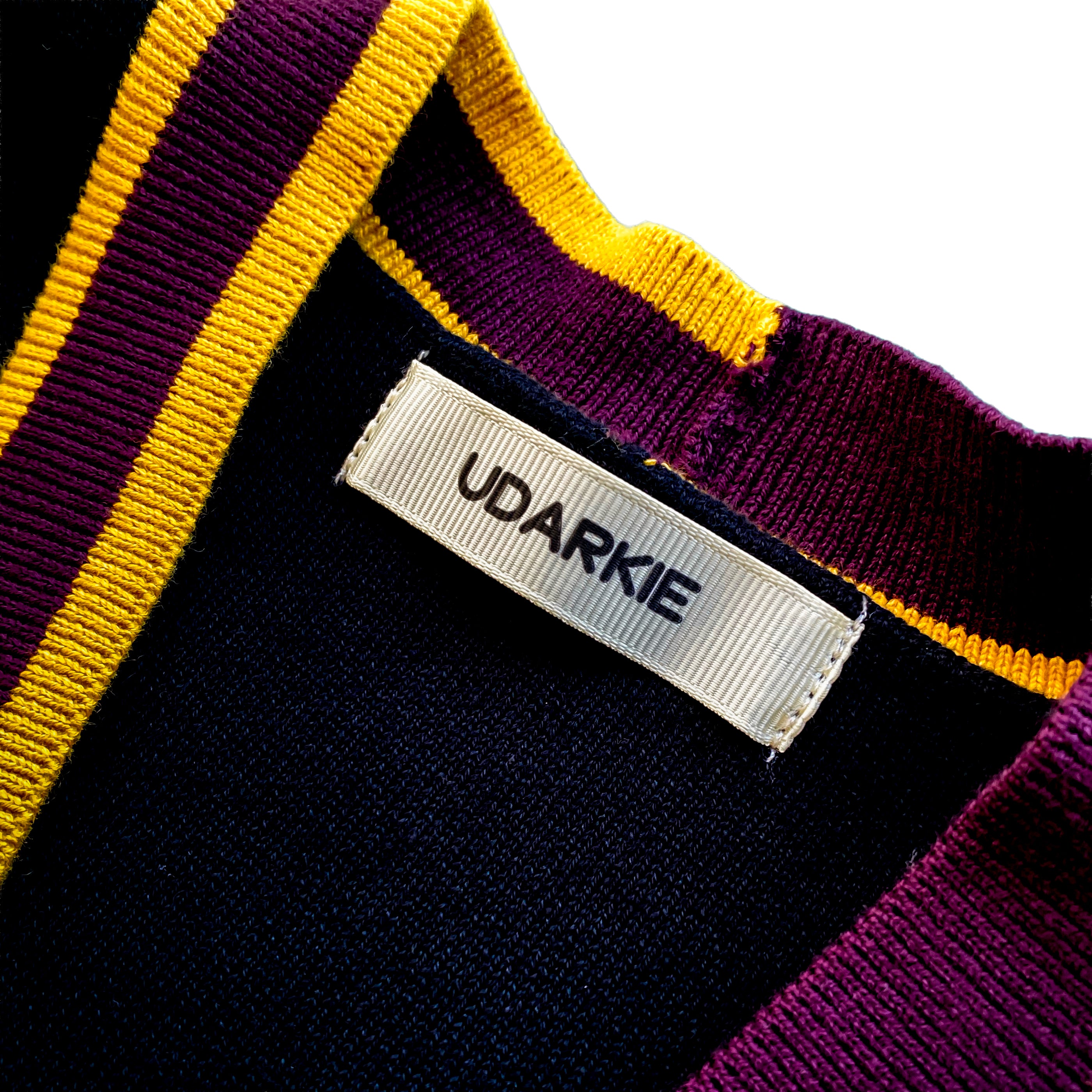 Close-up of a UDARKIE brand label on a varsity-style cardigan