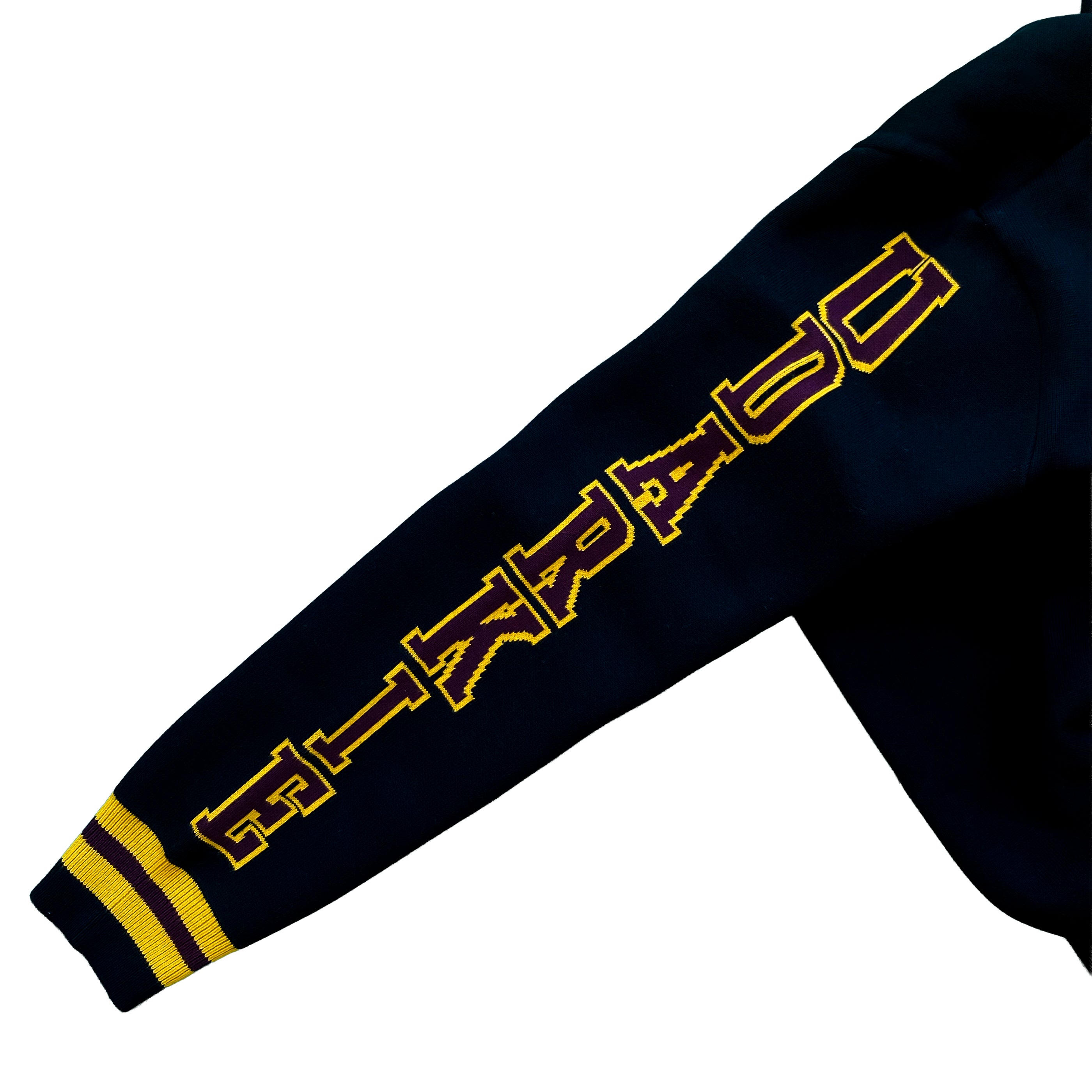 Close-up of a black varsity-style jacket sleeve with yellow "UDARKIE" text and two yellow stripes near the cuff.