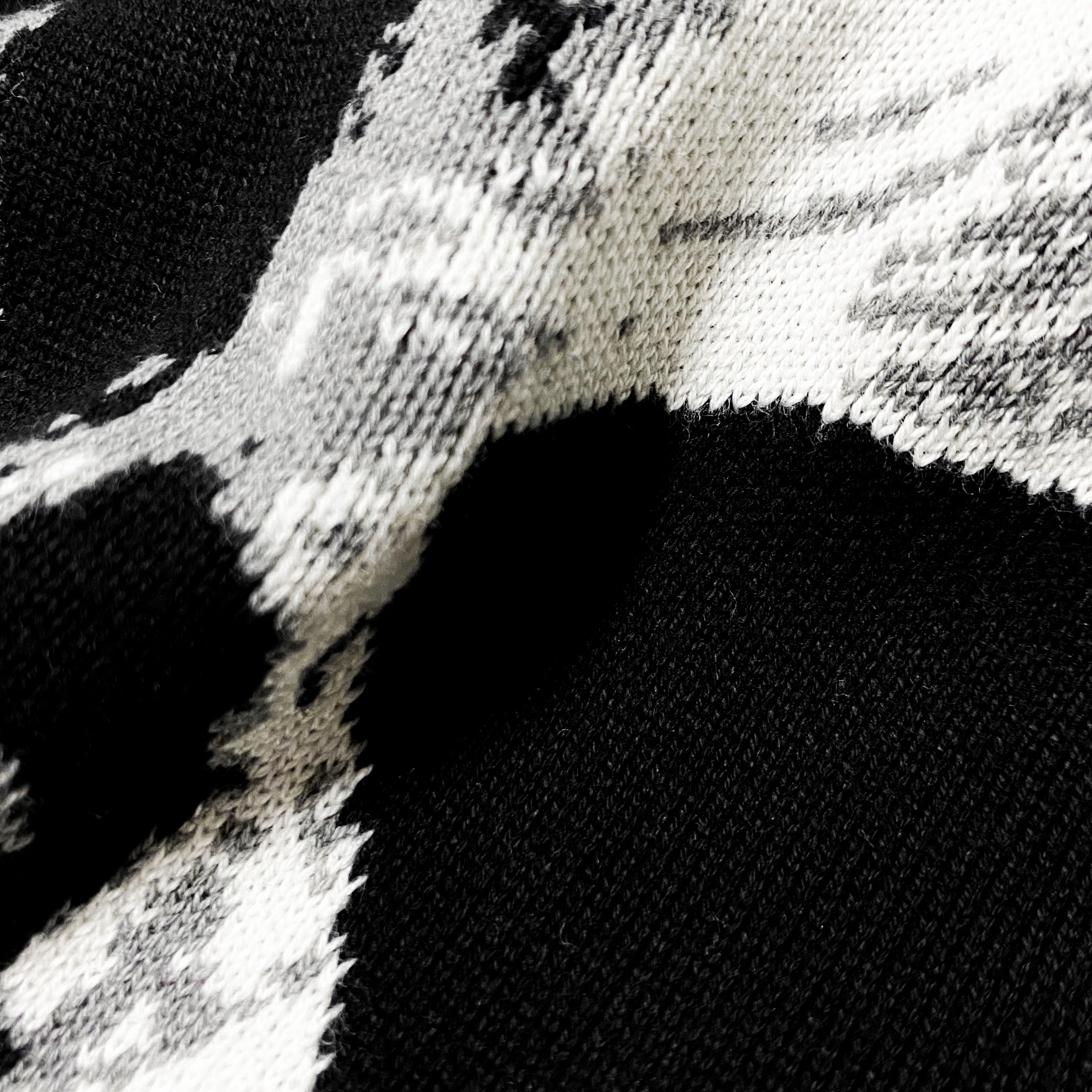 Close-up of black and white knitted fabric with abstract pattern and visible texture
