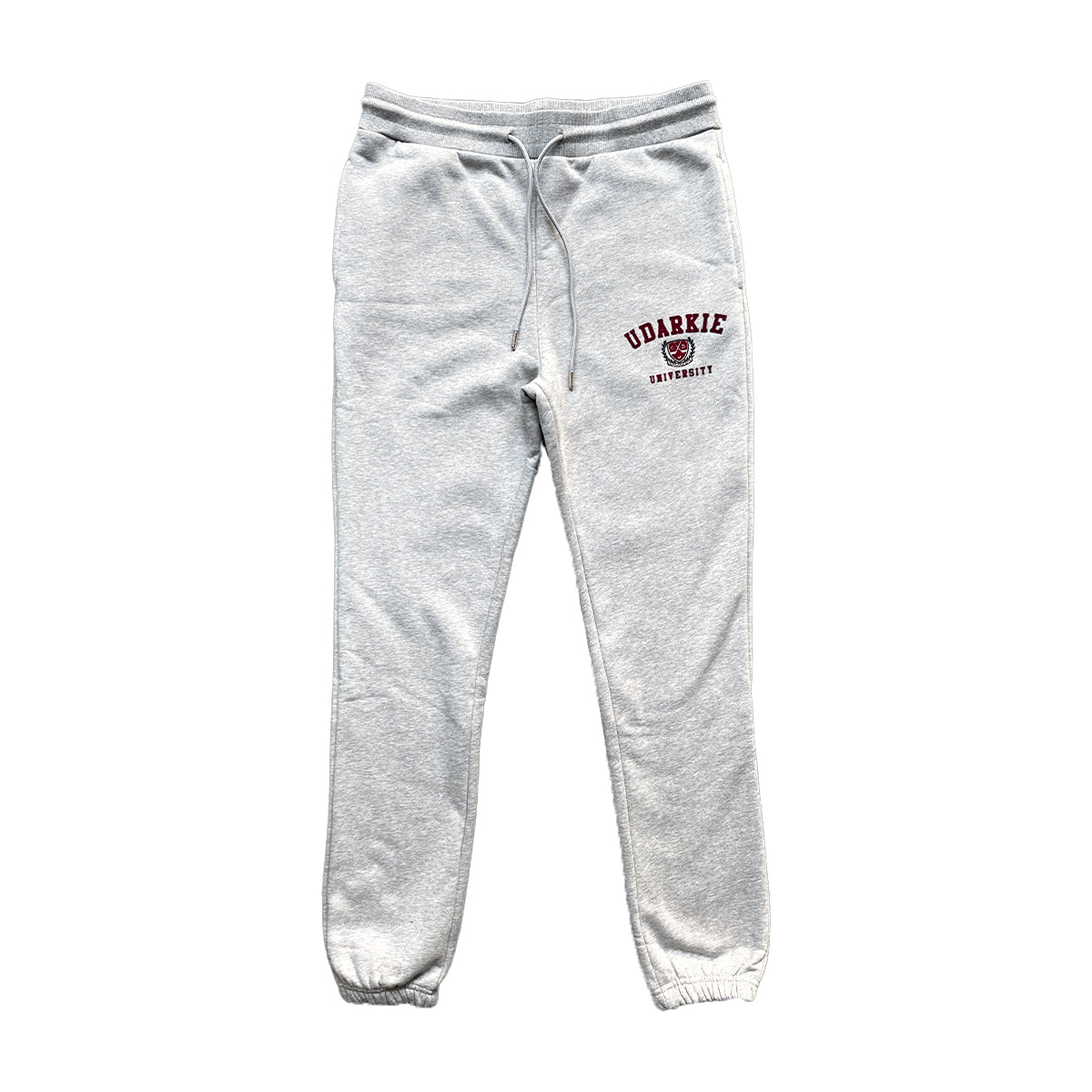 Grey sweatpants with elastic waistband, with maroon "UDARKE UNIVERSITY" text and emblem on the upper left thigh