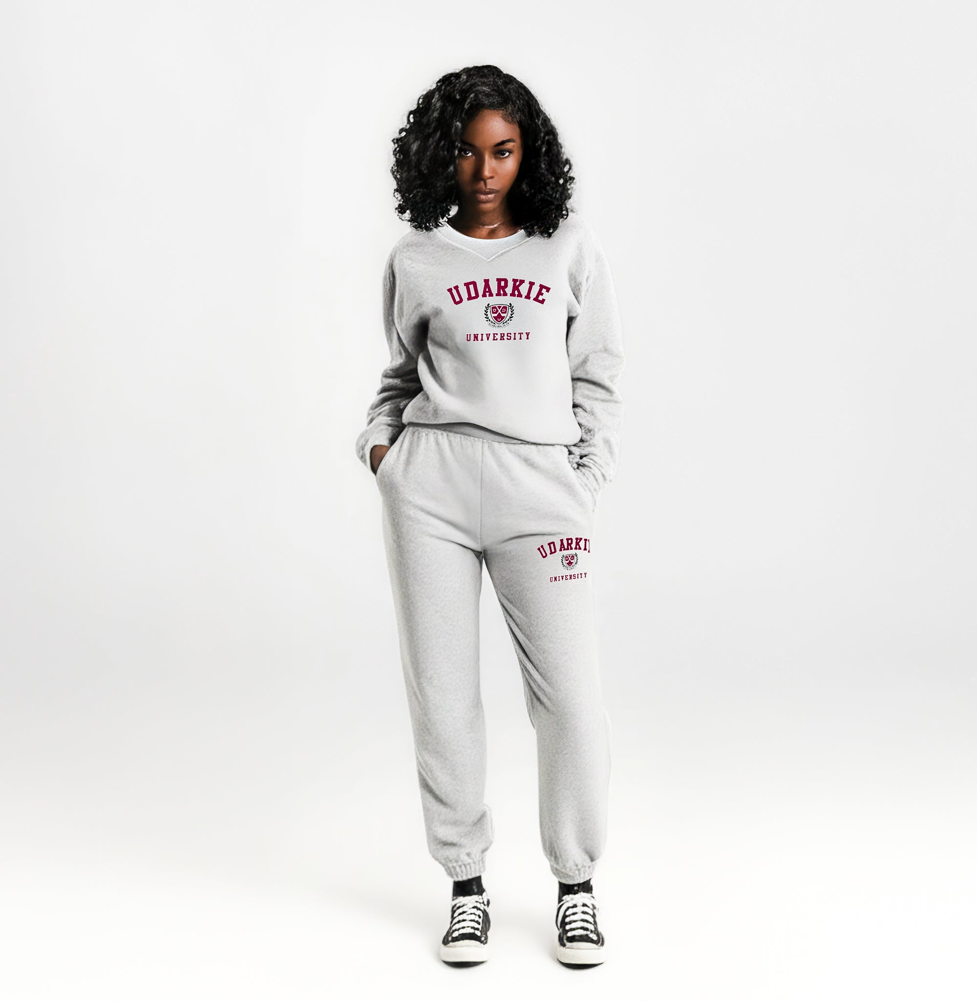 Front view of a person wearing a matching gray sweatshirt and sweatpants set with "UDARKIE UNIVERSITY" in red letters on both pieces