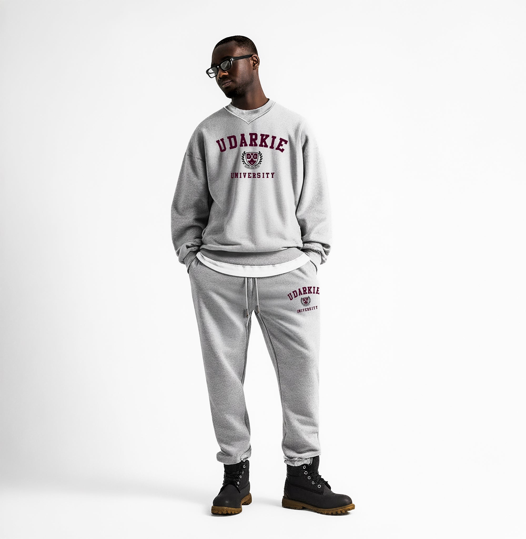 Front view of a man wearing a gray UDARKIE UNIVERSITY sweatsuit with maroon text and logo on both sweatshirt and sweatpants