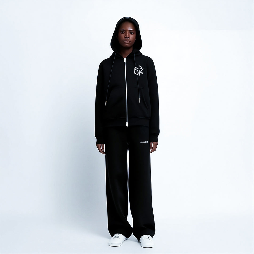 Front view of a person wearing a black "UDK" hoodie and black pants with "UDARKIE" text near the pocket, paired with white sneakers