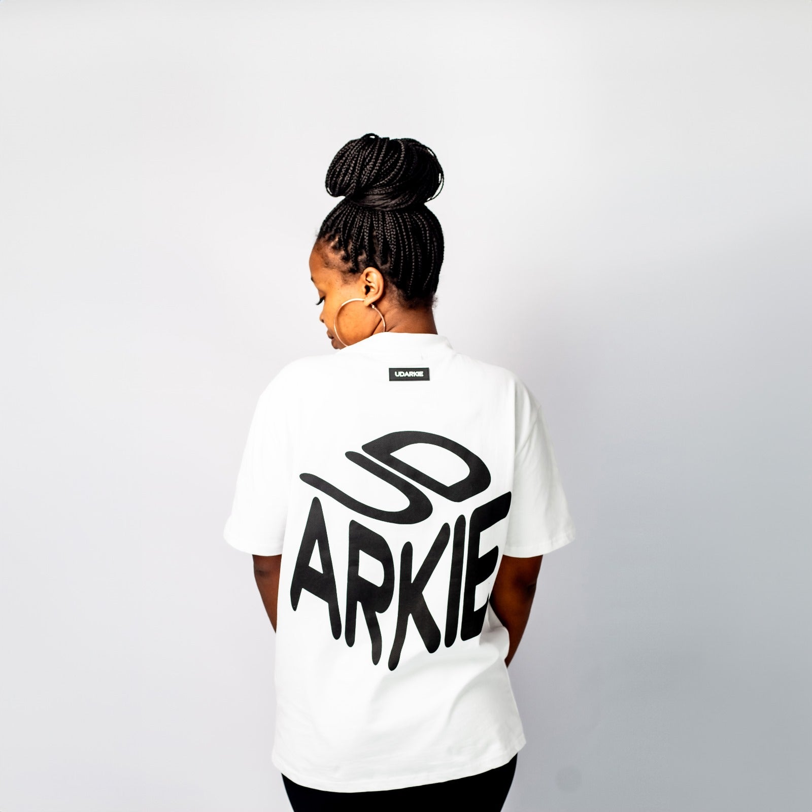 Back view of a white T-shirt with large white stylized text reading "UD ARKIE".