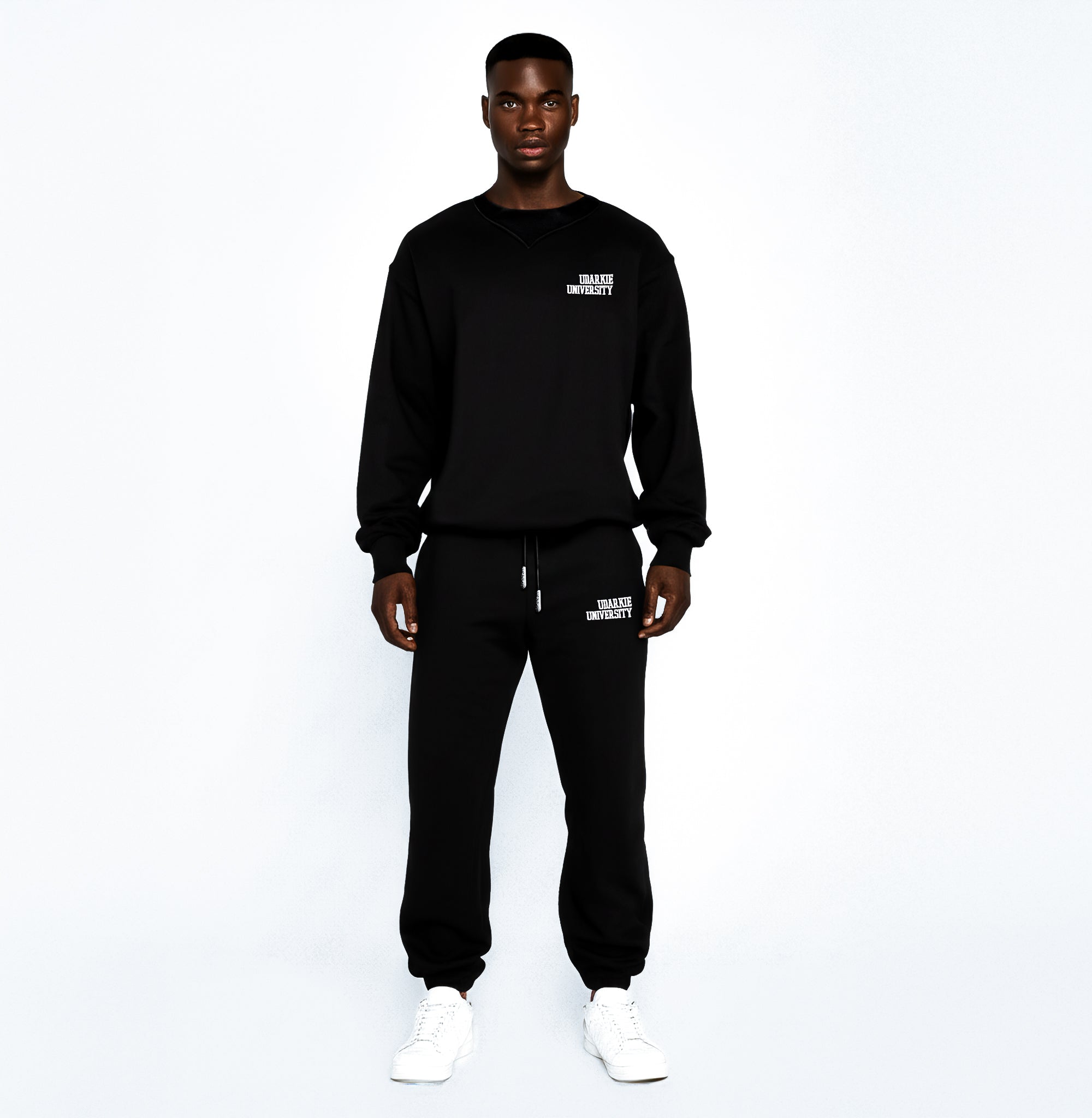 Full-body view of a Men wearing a black sweatshirt and sweatpants set with white "UDARKIE UNIVERSITY" print, standing against a white background.