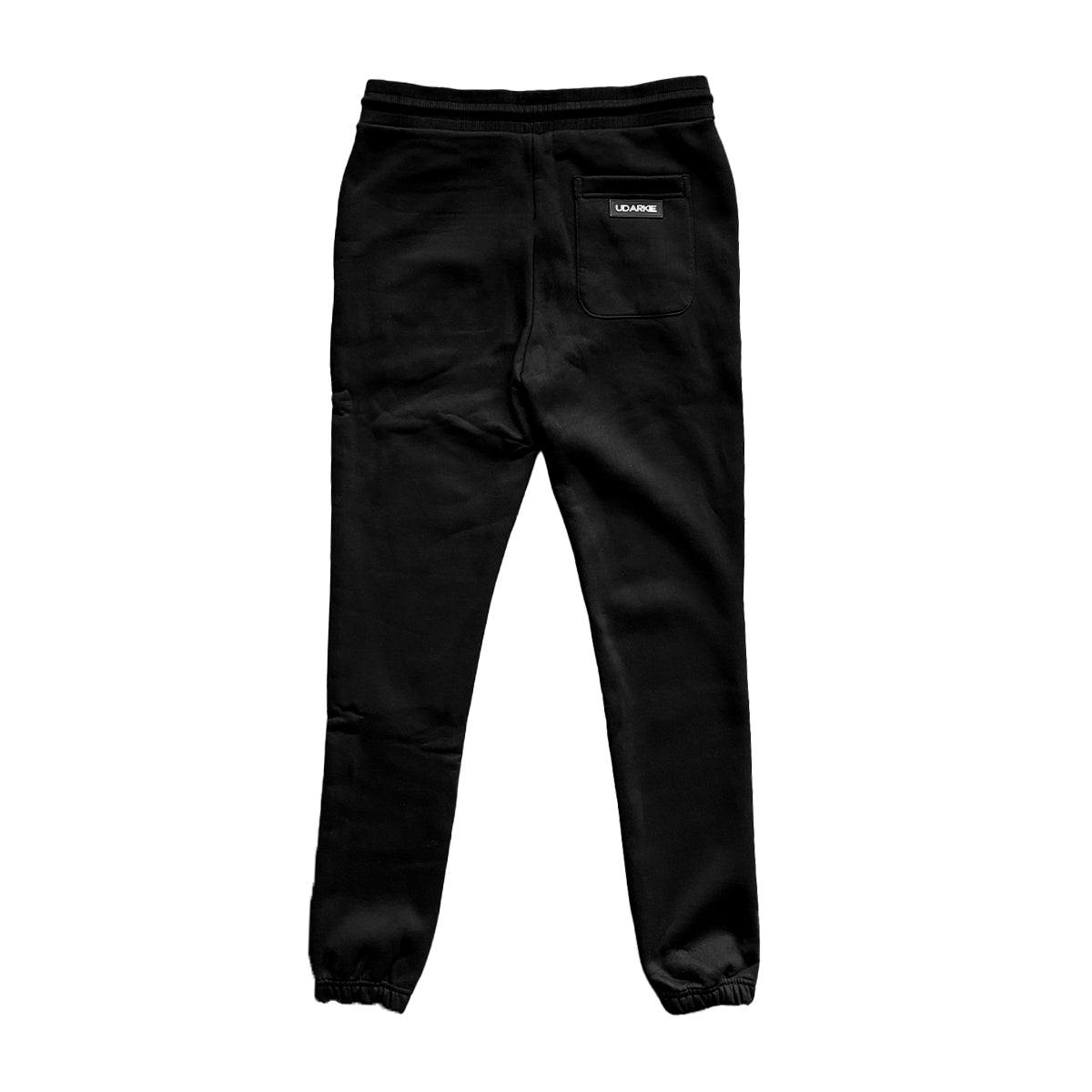Back view of black jogger pants with elastic waistband and cuffs, featuring a single back pocket and "UDARKIE" label.