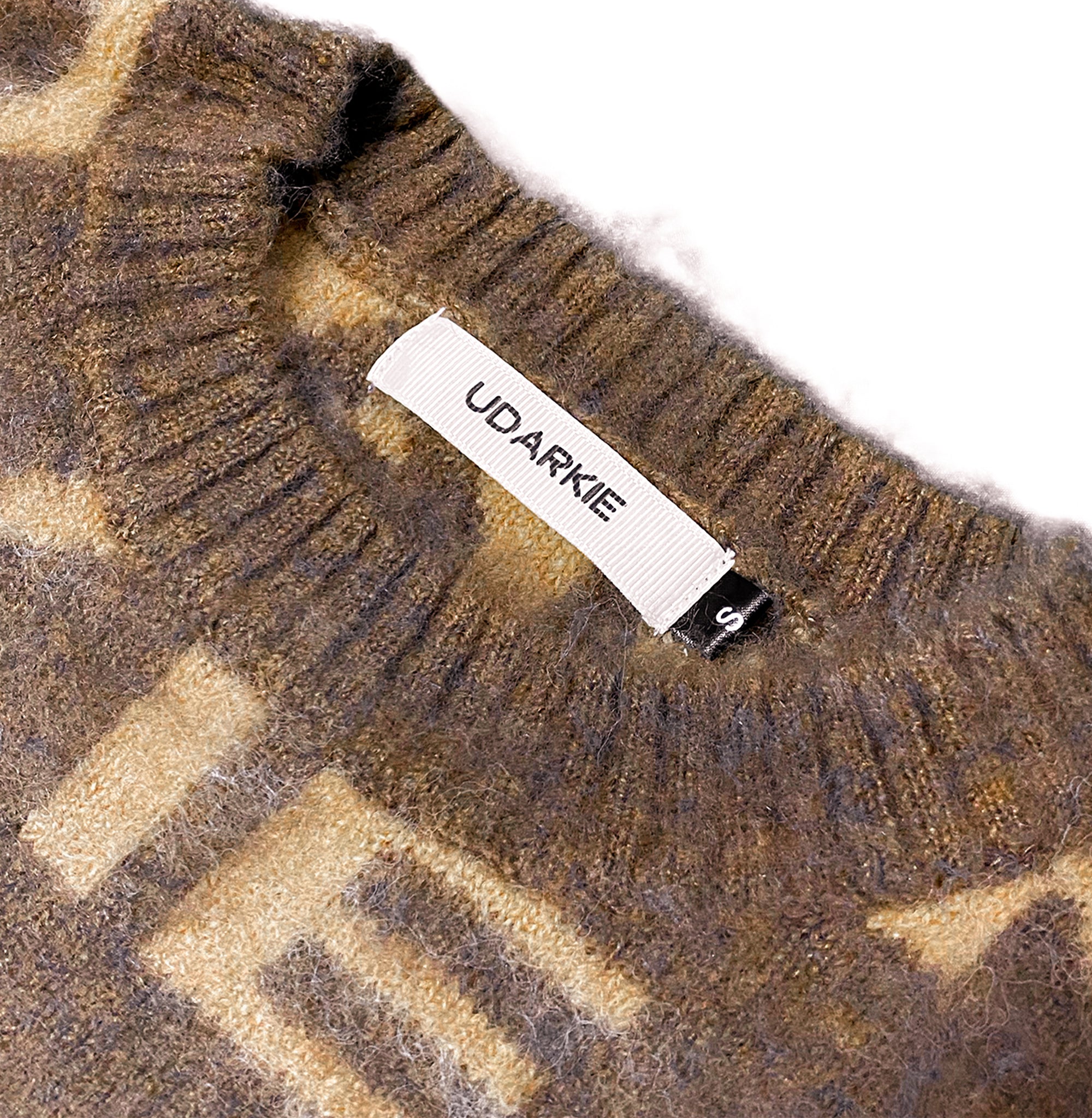Close-up of the collar of a fuzzy brown and beige knitted garment with a white "UDARKIE" label and a small black size tag marked "S".