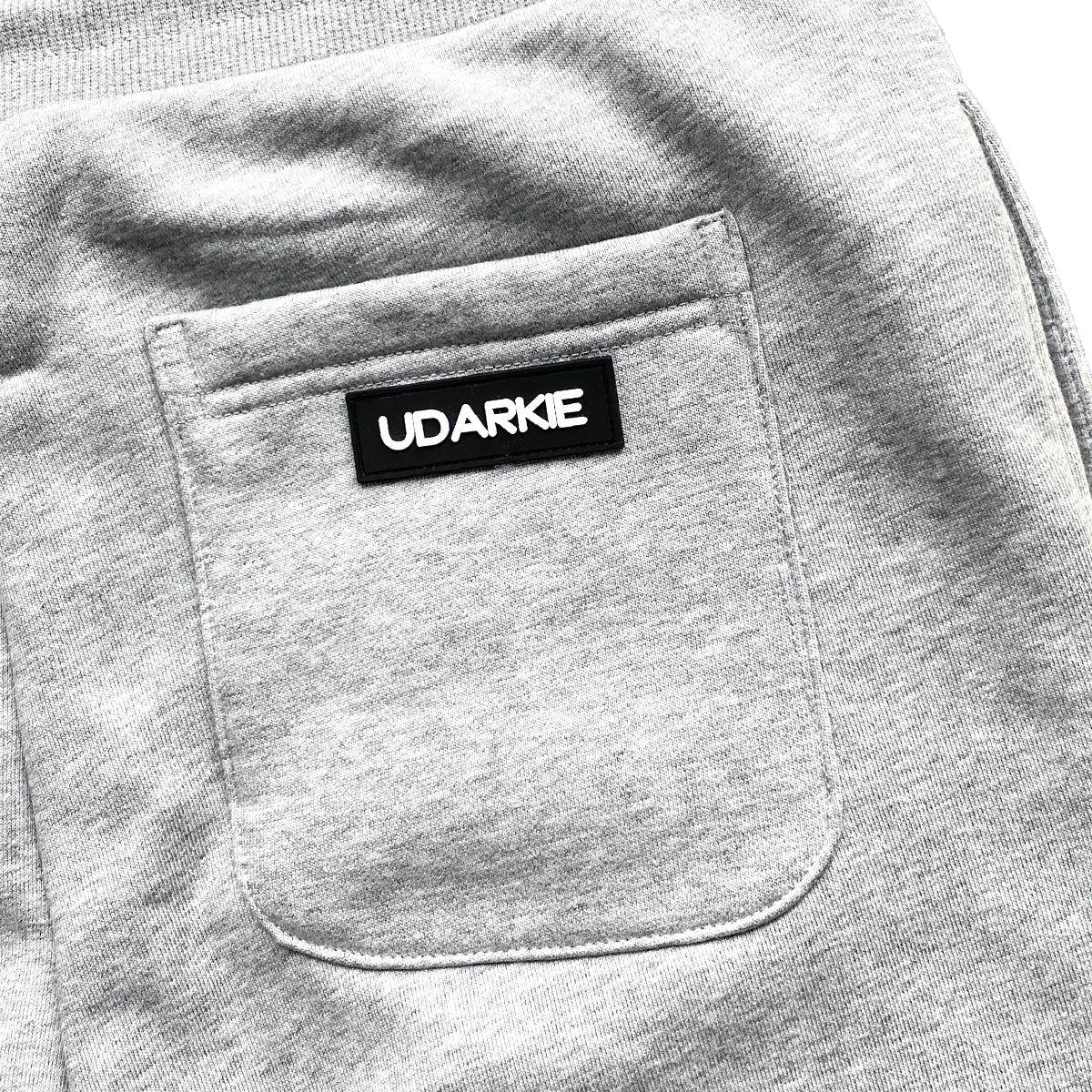 Close-up of gray fabric pocket with black sewn label displaying "UDARKIE" in white capital letters.
