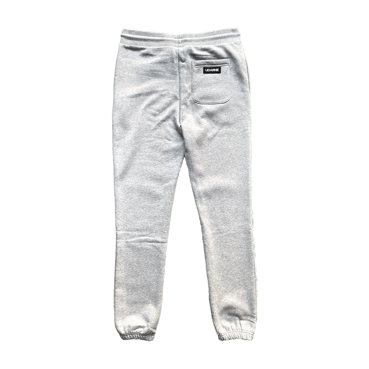 Back view of gray sweatpants with elastic waistband and cuffs, with a black label above the right pocket that reads "UDARKIE"