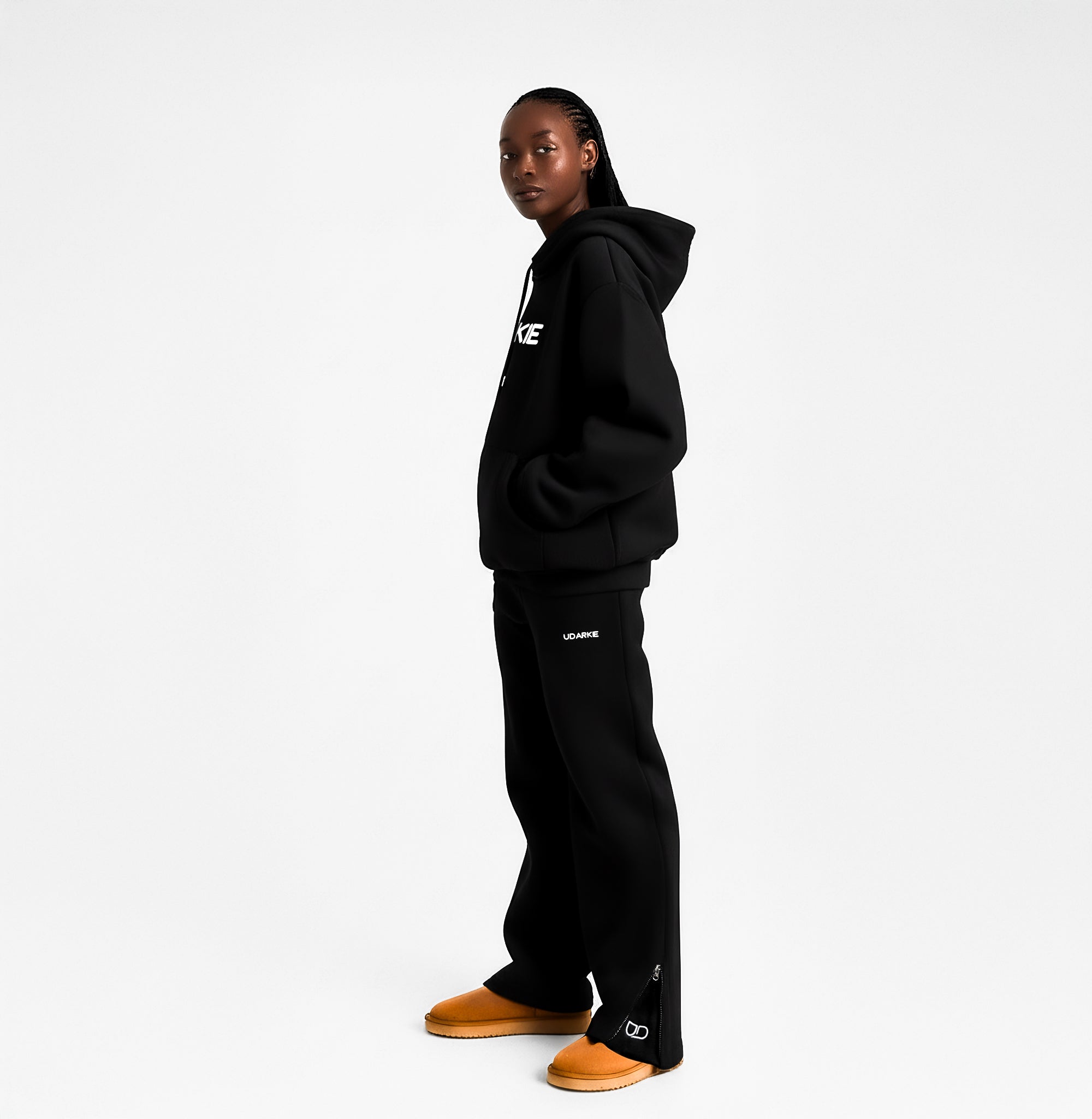 Black trackpants with drawstring waist, "UDARKIE" logo on upper thigh, and zippered ankles.