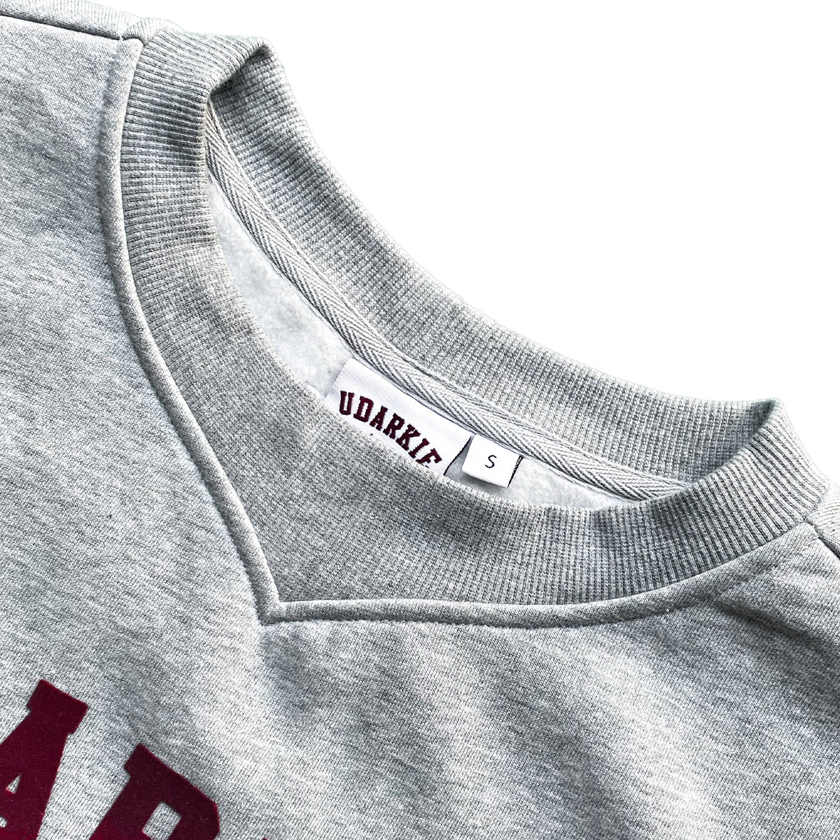 Close-up of gray sweatshirt neckline showing "UDARKIE" brand label in maroon and size "S", with partial maroon text visible on the fabric